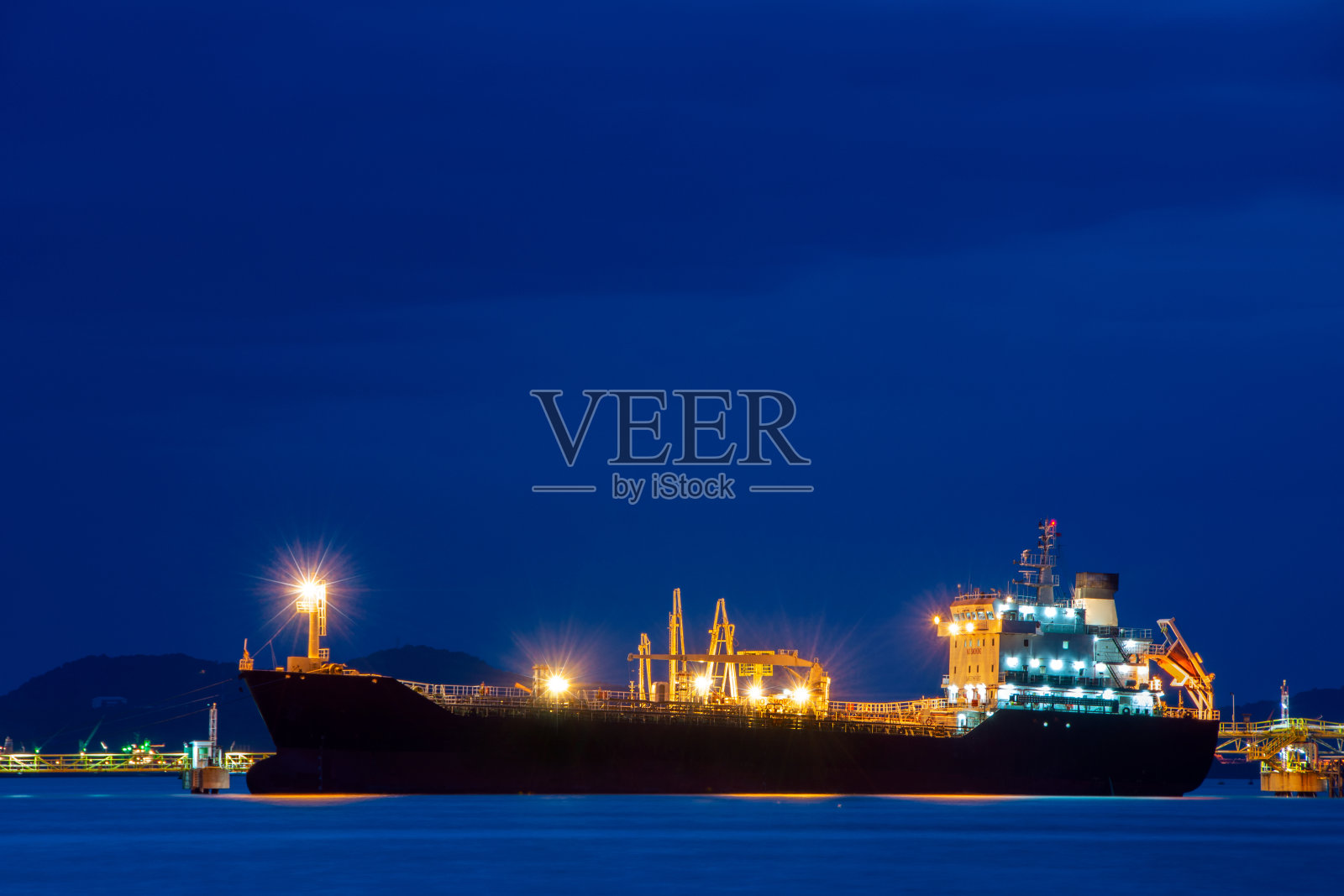 夜间停靠在港口货运站的货船。照片摄影图片
