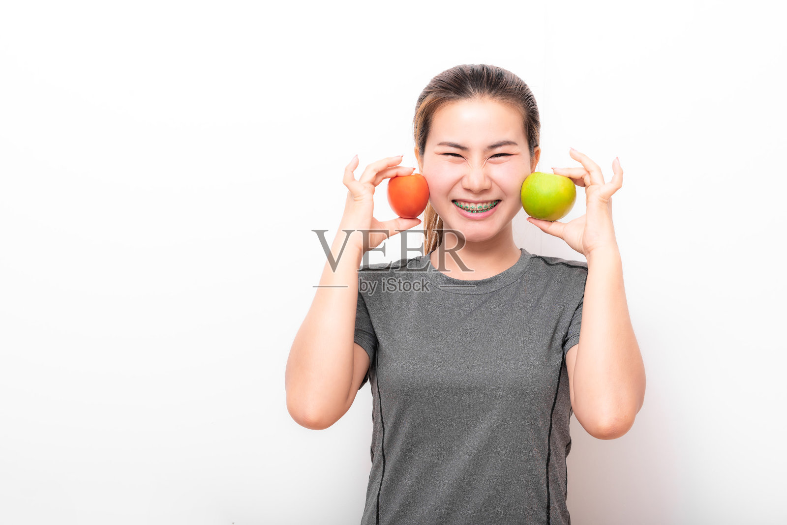 戴牙套的女人喜欢吃青苹果和西红柿照片摄影图片