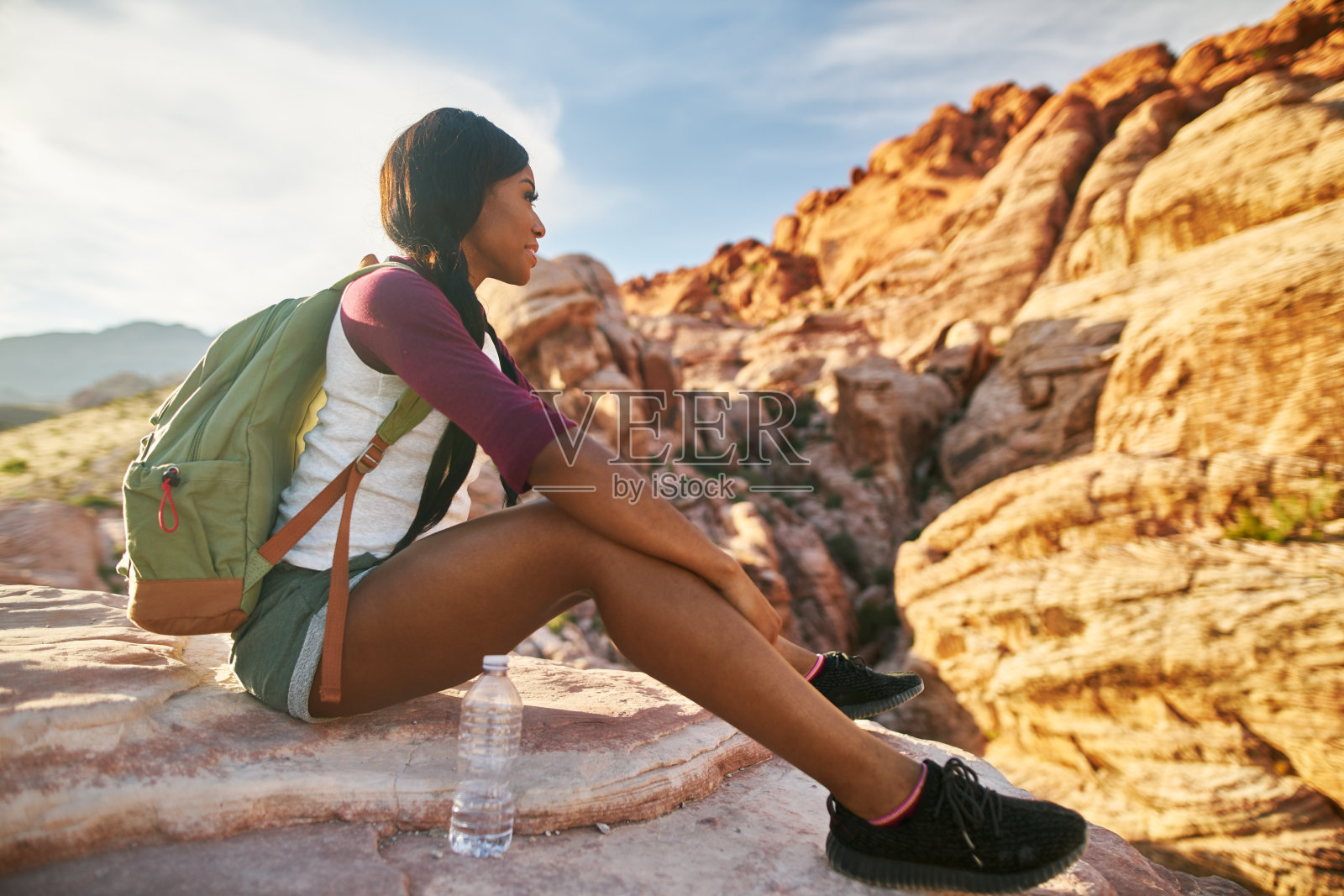 运动女性背包客坐在悬崖边享受红岩峡谷的景色照片摄影图片