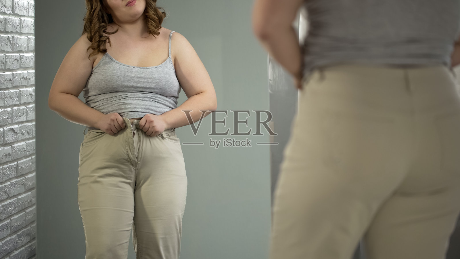 胖女人想穿裤子，结果吃得太多，消化失调照片摄影图片