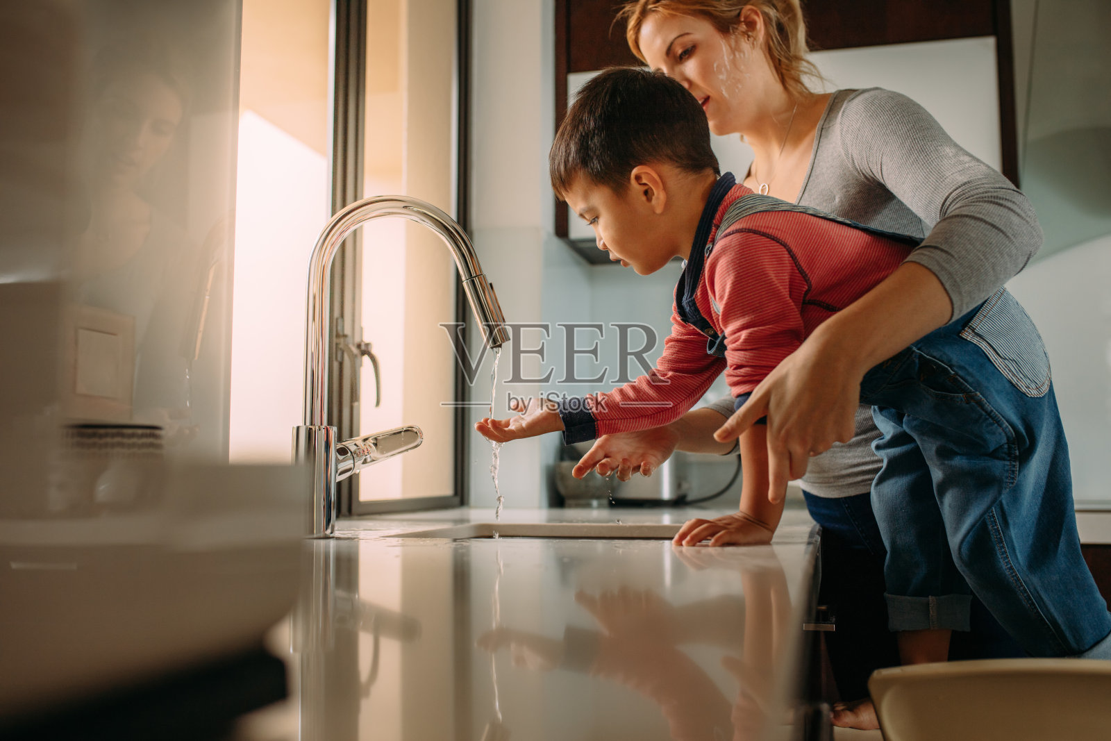 小男孩和妈妈在厨房水槽洗手照片摄影图片