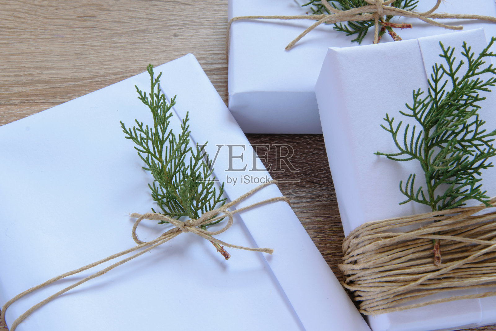 顶视图的白色手工礼盒和新鲜的杉木树枝在木制背景，季节性的庆祝和环保的概念照片摄影图片