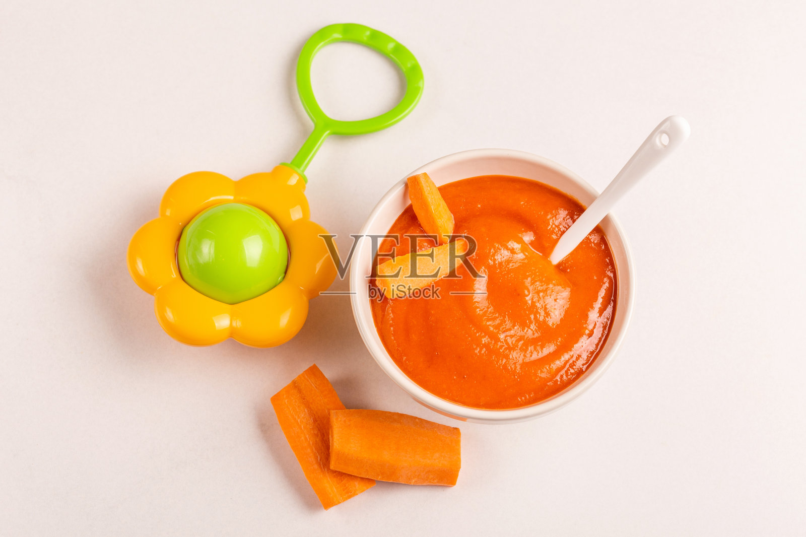 胡萝卜泥婴儿食品在粘土碗与生胡萝卜和豆袋在白色大理石背景照片摄影图片