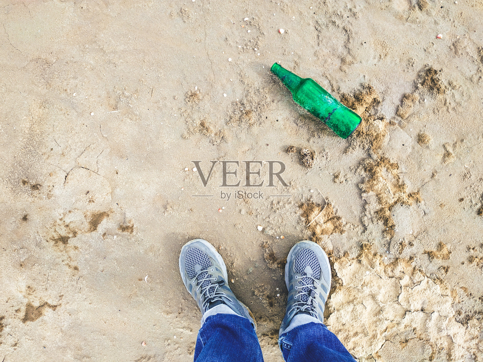 沙子里的绿色空玻璃瓶。口渴了，找水喝照片摄影图片
