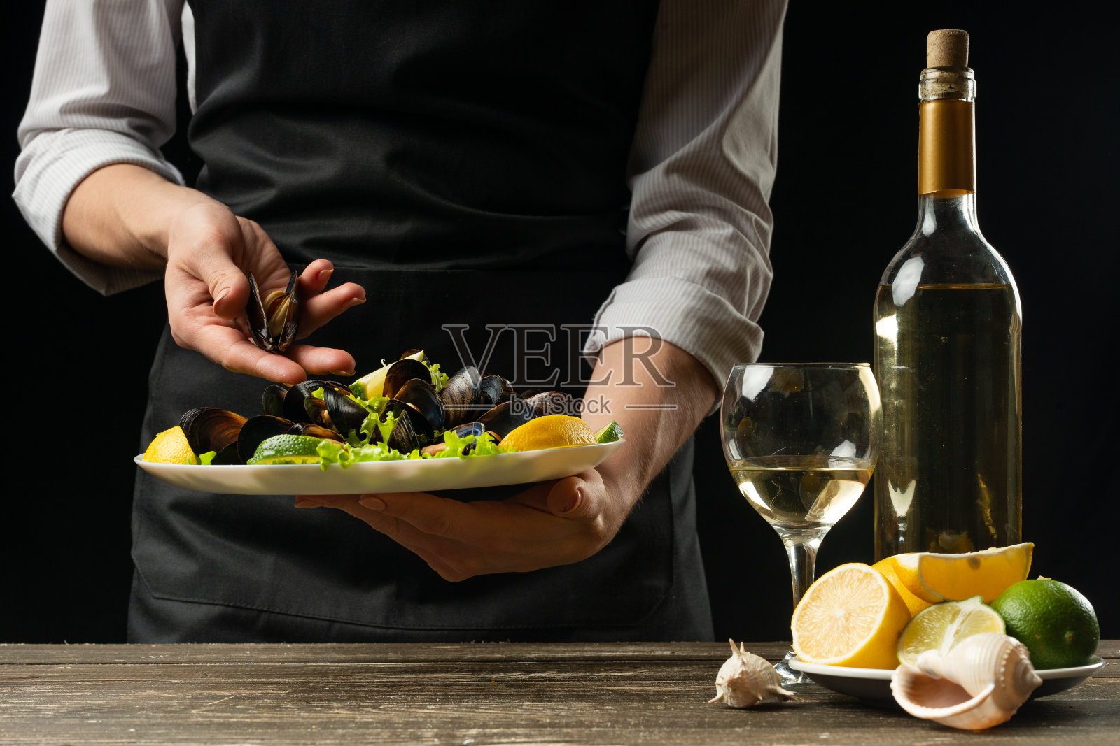 厨师正准备用白葡萄酒做沙拉用贻贝，在深色的背景上做设计，水平照片。烹饪的概念，食谱，餐厅和海鲜照片摄影图片
