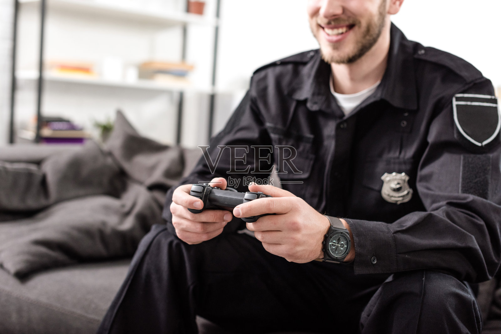 用游戏手柄坐在沙发上玩电子游戏的警察照片摄影图片