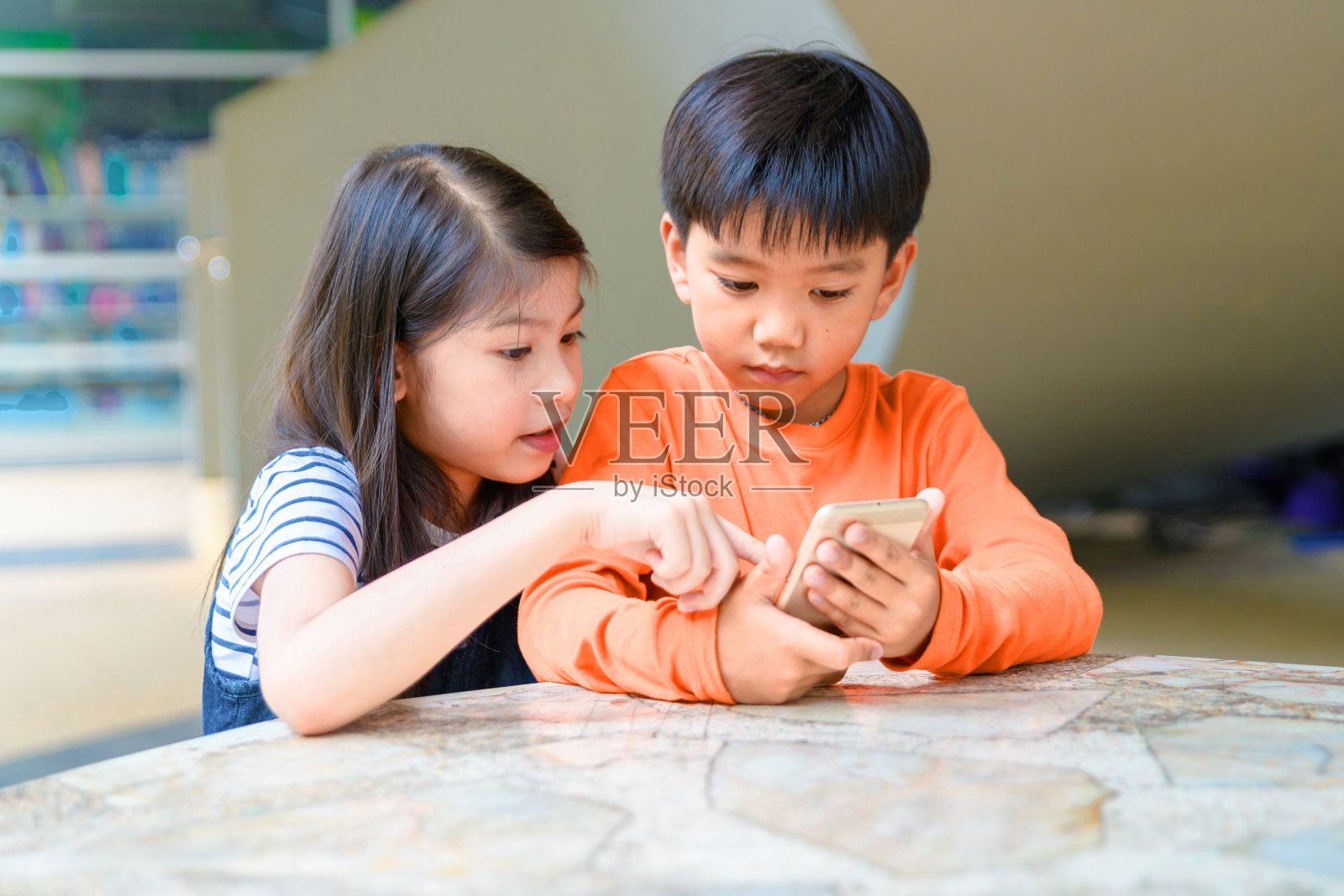 可爱的小亚洲儿童使用手机，玩游戏，一起看视频电影坐在户外的台阶上照片摄影图片