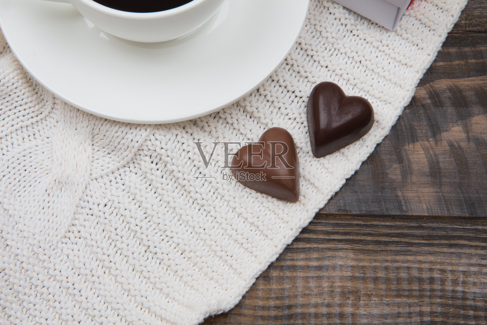 两个心形的巧克力。白色格子和深色木质背景照片摄影图片