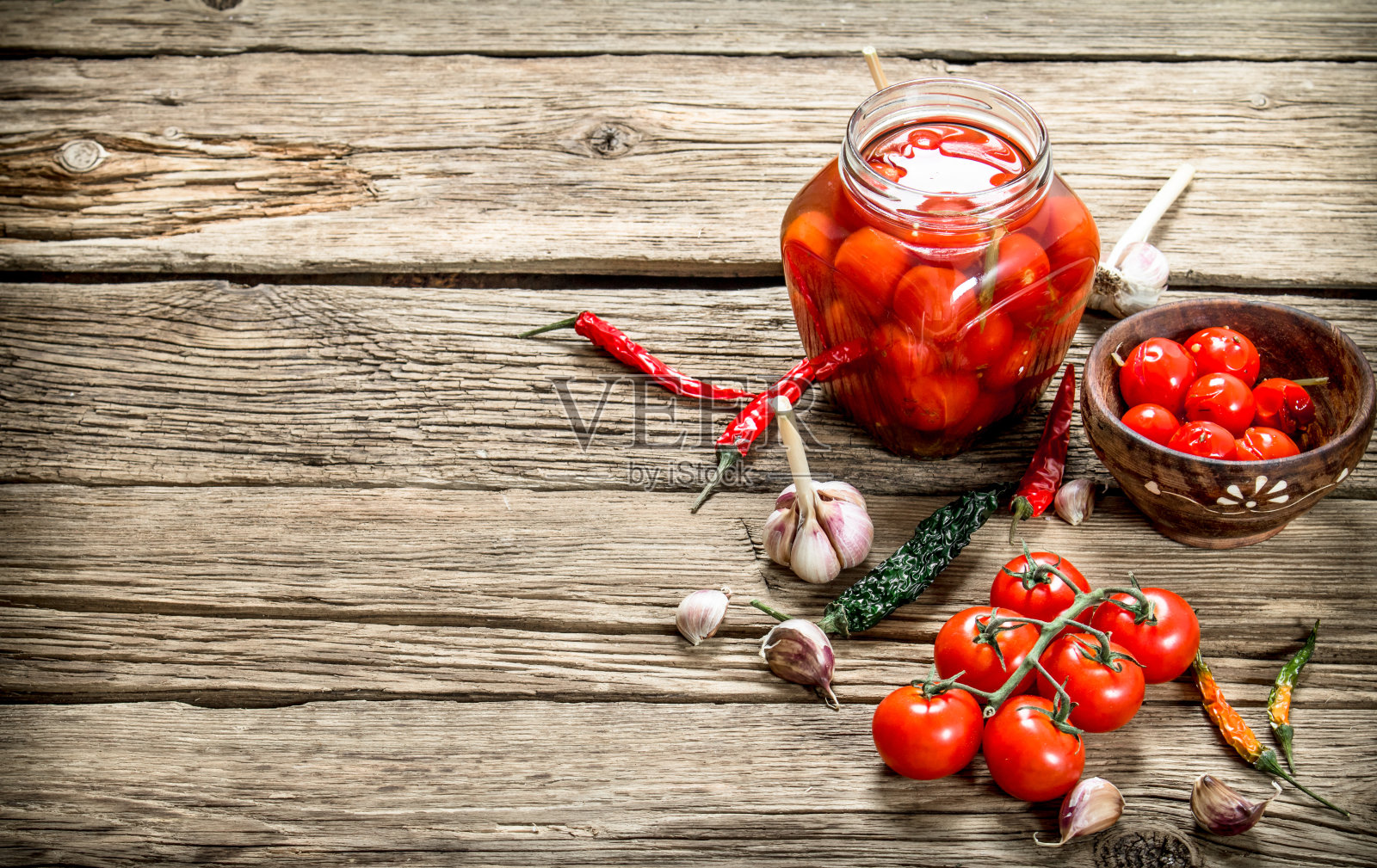 玻璃罐里的腌西红柿，还有大蒜和香草。照片摄影图片