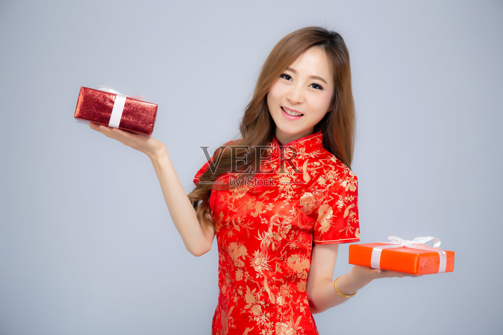 新年快乐美丽的肖像年轻的亚洲女人拿着红色的礼盒孤立在白色的背景，女孩的微笑和显示礼物购买，节日的概念。照片摄影图片