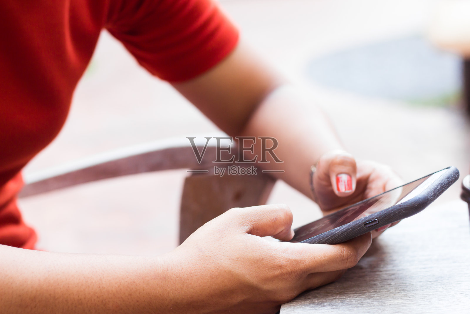 小女孩在一张木桌上玩手机上网。照片摄影图片