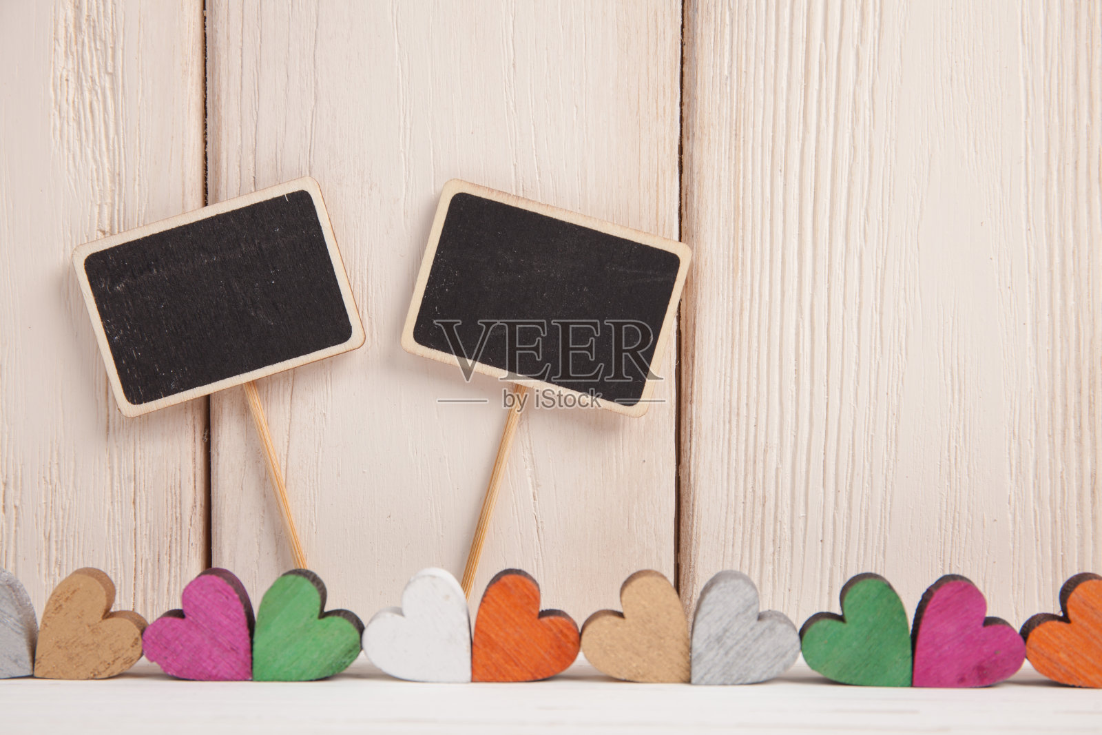 情人节的概念。一个彩色的心和两个黑色的木板上的文字在一个白色的木头背景。照片摄影图片