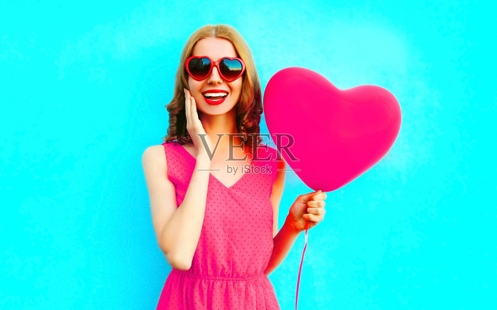 肖像快乐的笑年轻女子与粉红色的心形气球在蓝色的背景照片摄影图片
