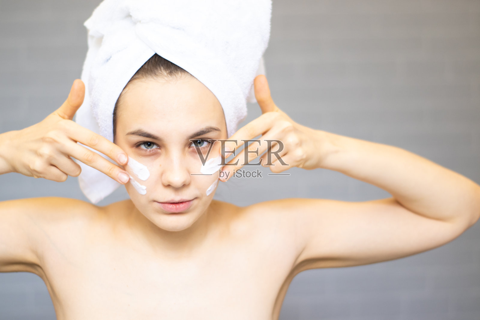一名年轻女子沐浴后用浴巾裹着面霜照片摄影图片