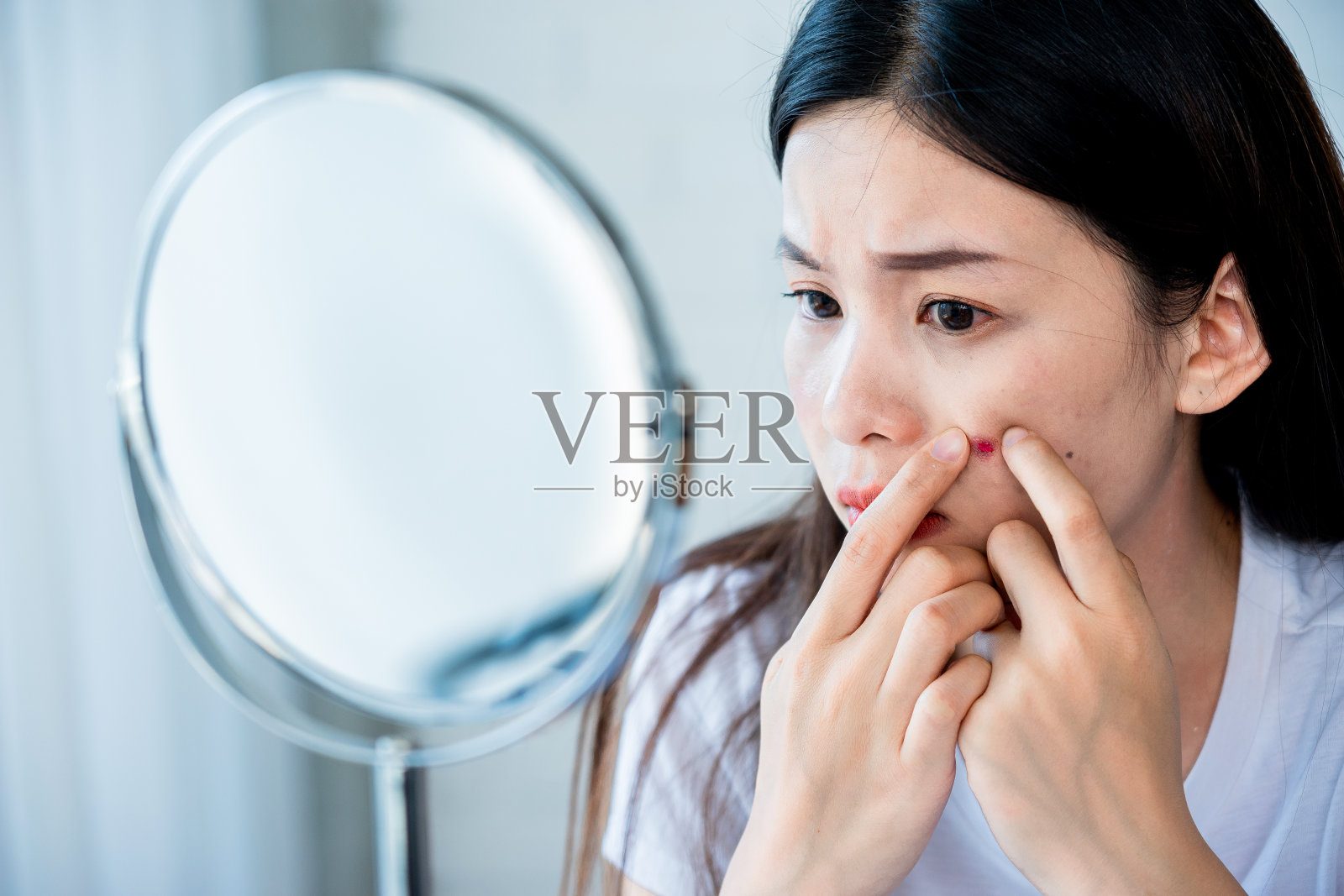 亚洲少女妇女看着镜子和挤压痤疮问题在她的脸上照片摄影图片