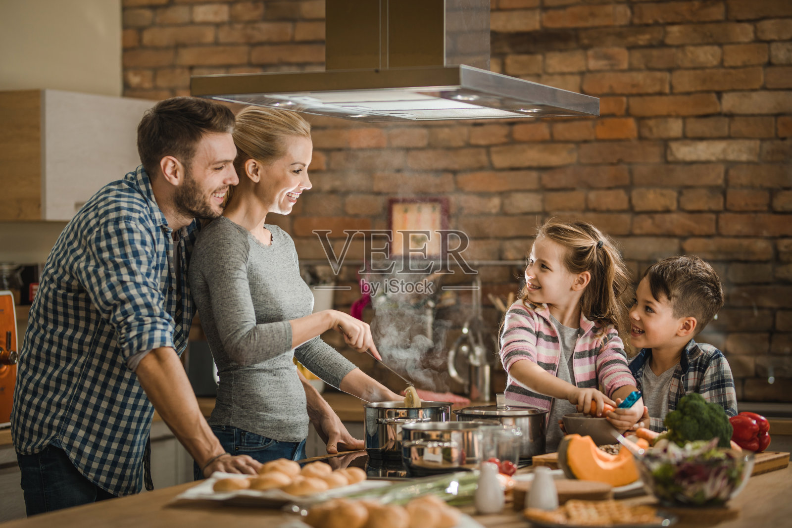 快乐的家庭在厨房边做午餐边交流。照片摄影图片_ID:317405561-Veer图库