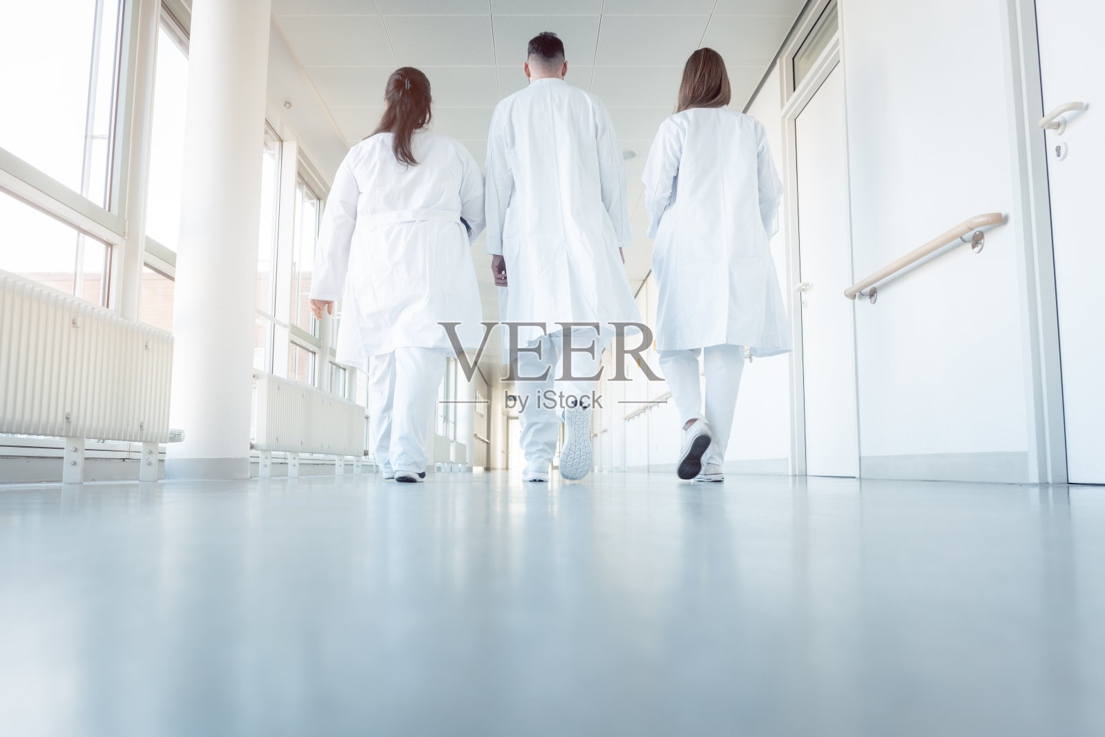 三个医生走在医院的走廊上照片摄影图片