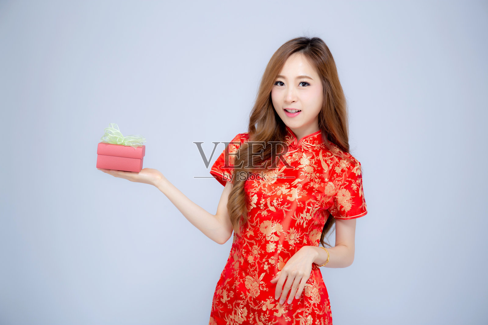 新年快乐美丽的肖像年轻的亚洲女人拿着红色的礼盒孤立在白色的背景，女孩的微笑和显示礼物购买，节日的概念。照片摄影图片