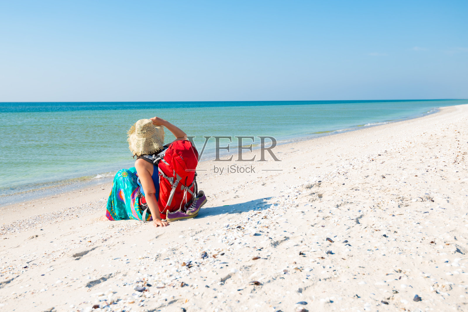 女人在一个pareo与背包放松在荒芜的海滩照片摄影图片