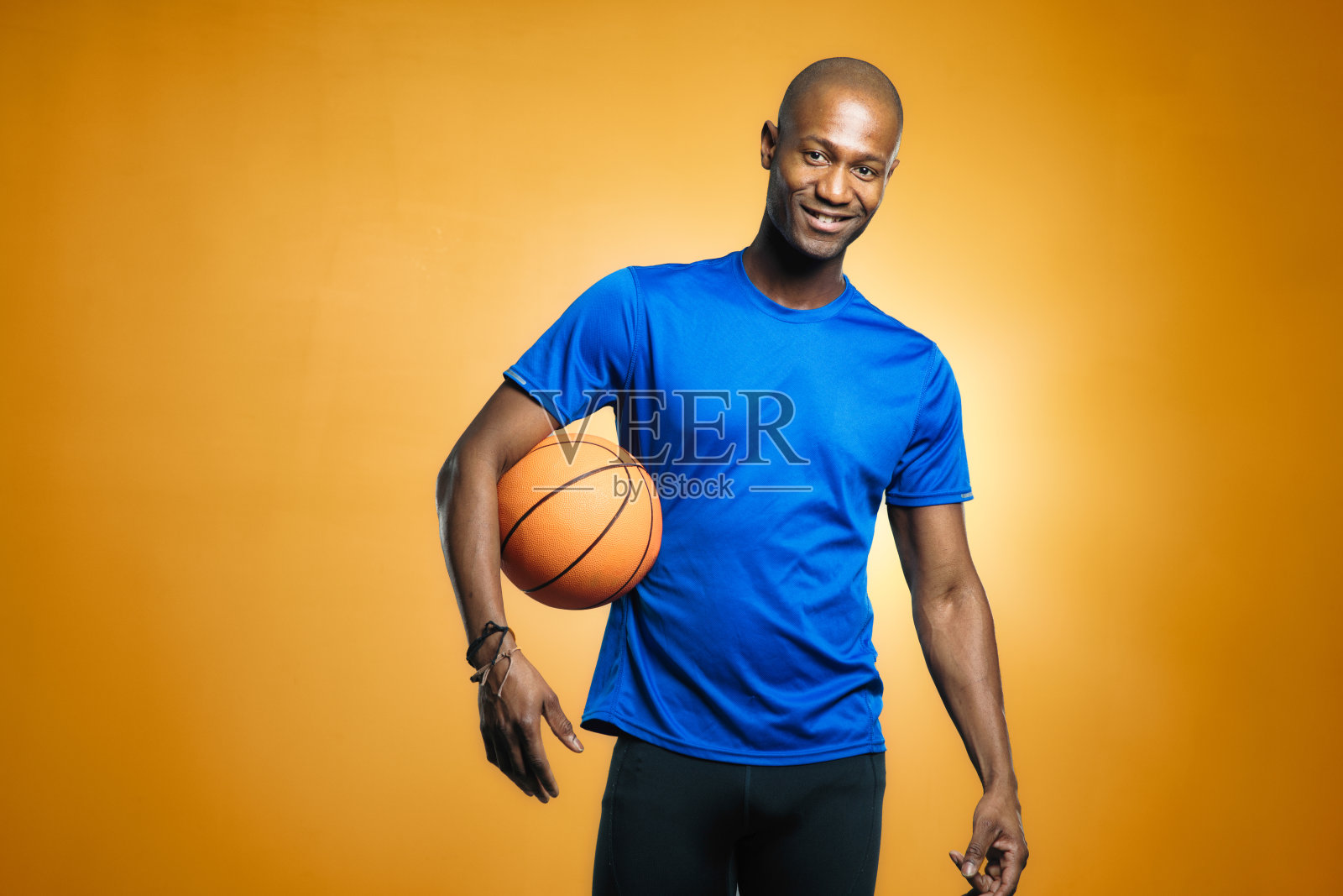 成熟的秃头黑人男子篮球运动员酷肖像与橙色背景照片摄影图片
