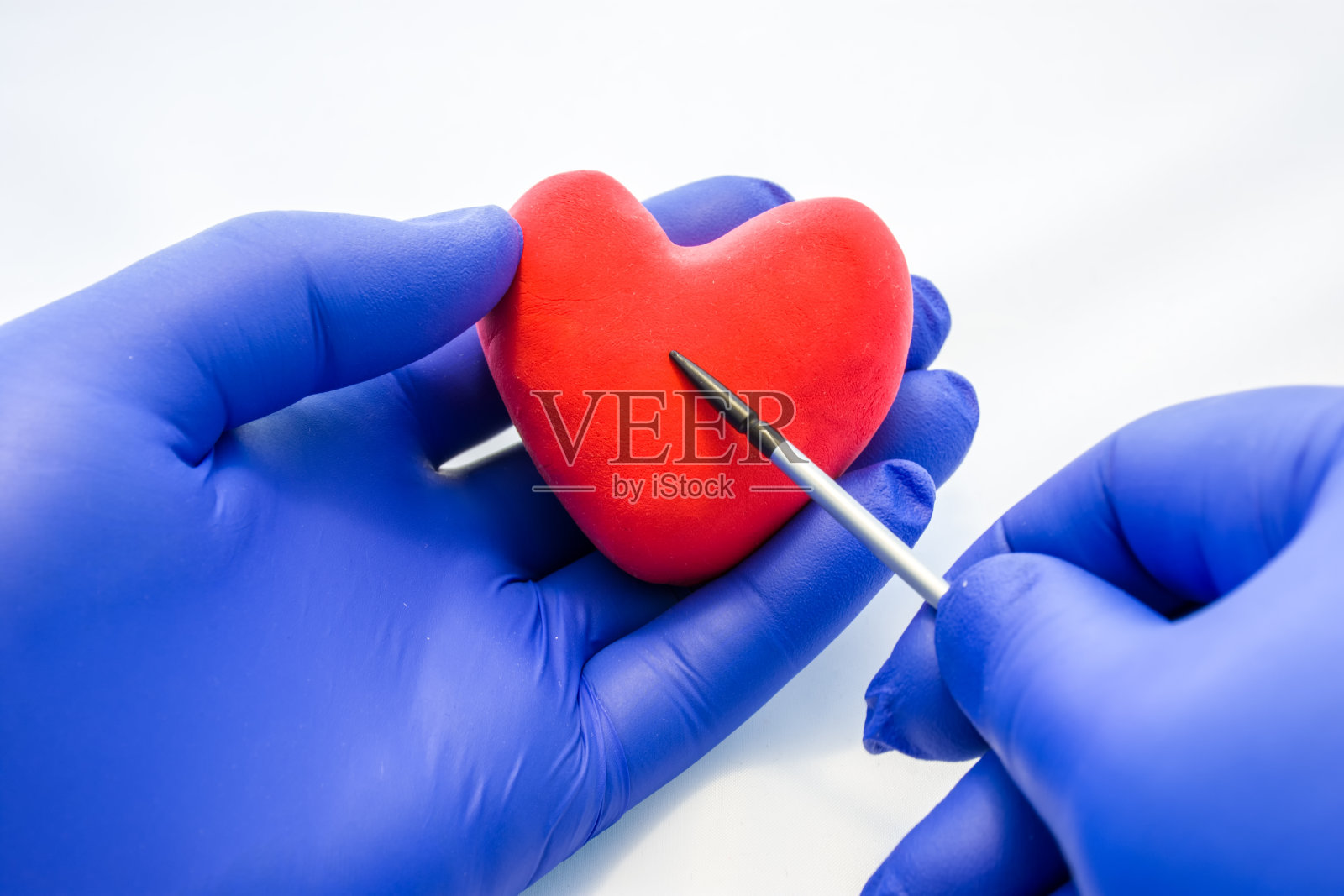 医生，科学家或生物学家拿着心脏形状的另一只手用指针指着它。对解剖学、心脏病学、心血管系统疾病和病理、诊断等方面的摄影思想照片摄影图片
