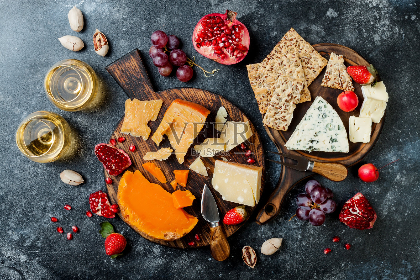 各种奶酪板或拼盘，搭配各种奶酪，葡萄，蜂蜜，坚果和葡萄酒。黑石的背景。俯视图，平放照片摄影图片