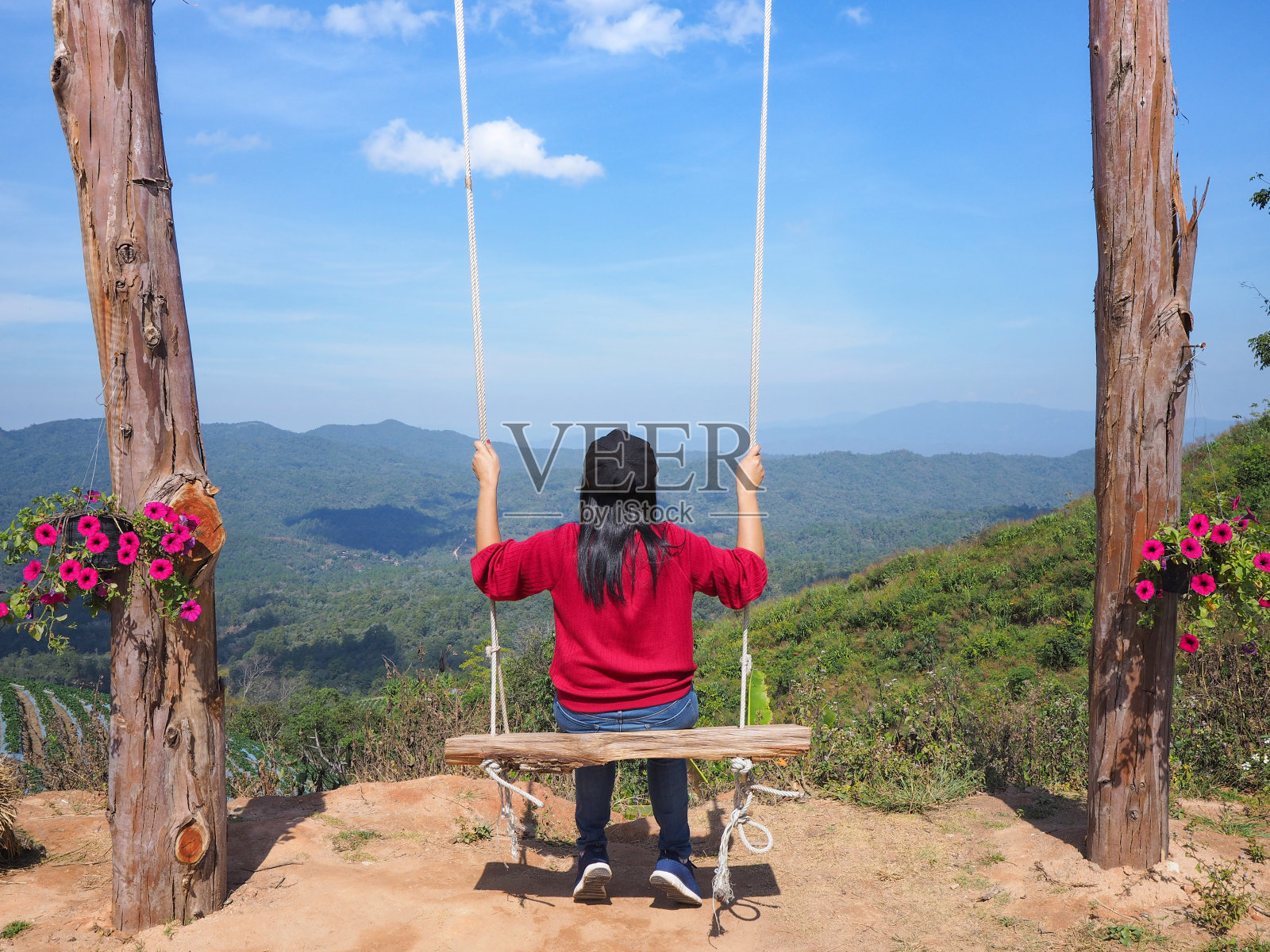 女游客坐在木秋千上看山景照片摄影图片