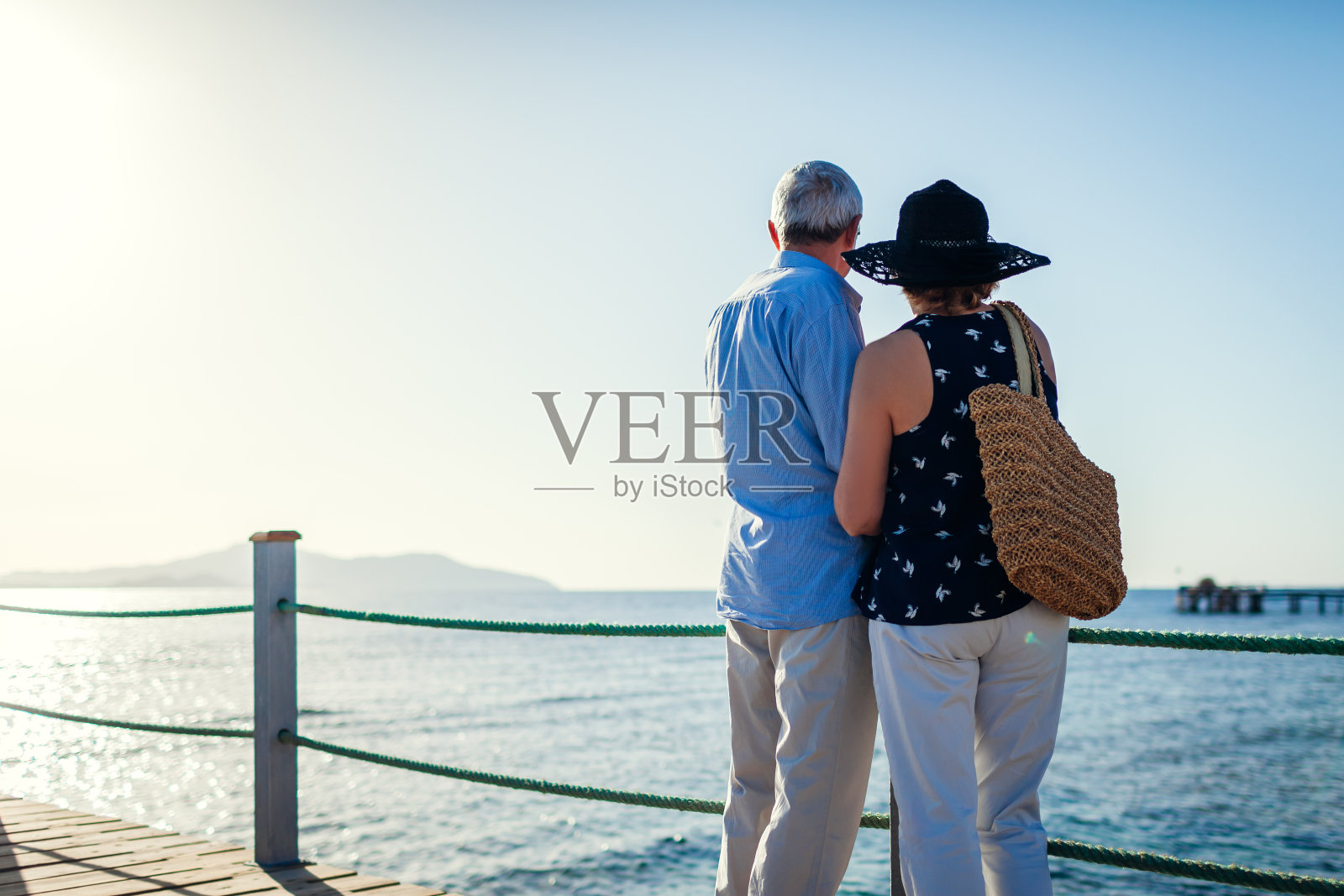 一对老年夫妇在红海边的码头上散步。人们享受暑假。照片摄影图片