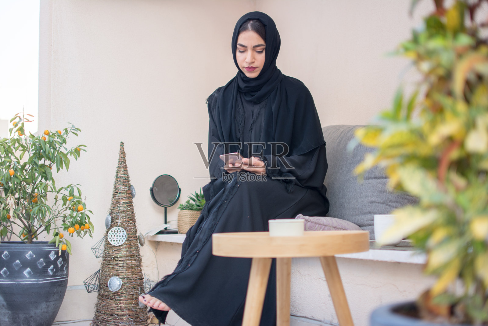 美丽的阿拉伯女人在阳台上休息时使用智能手机照片摄影图片