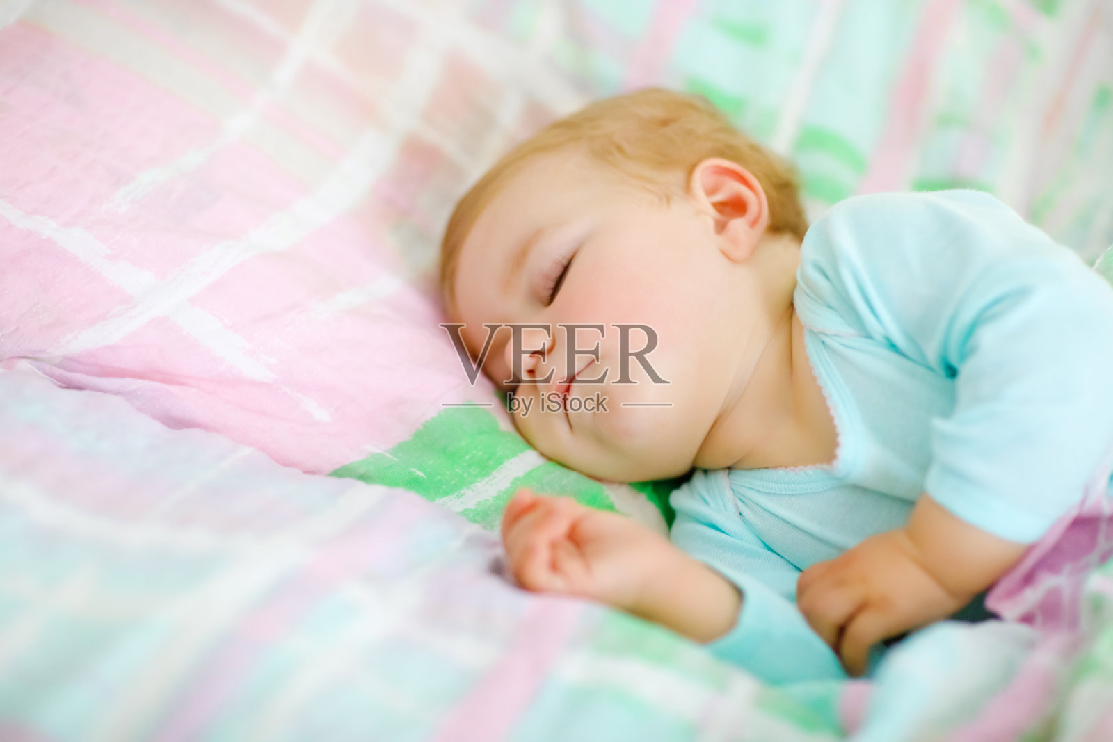 可爱的小女孩睡在床上。平静安详的孩子白天做梦睡觉。漂亮的宝宝在父母的床上。睡在一起的概念。照片摄影图片
