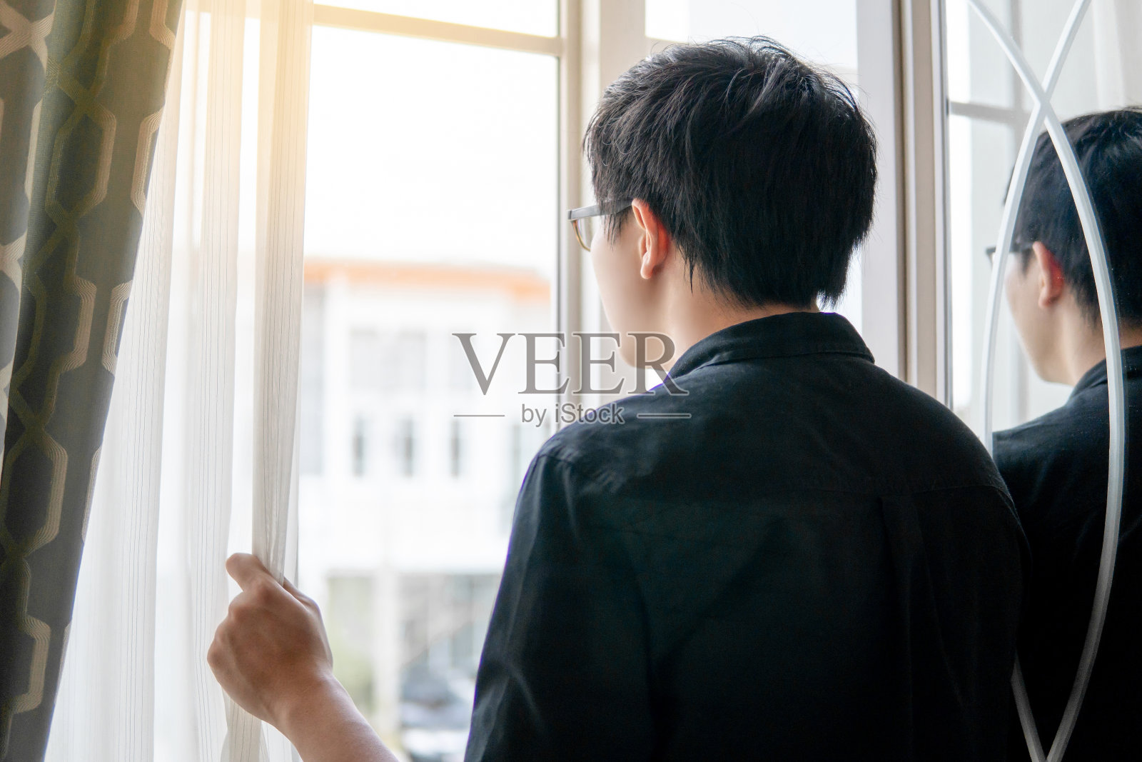 年轻的亚洲幸福的人拿着窗帘看着窗外。家居生活方式概念照片摄影图片