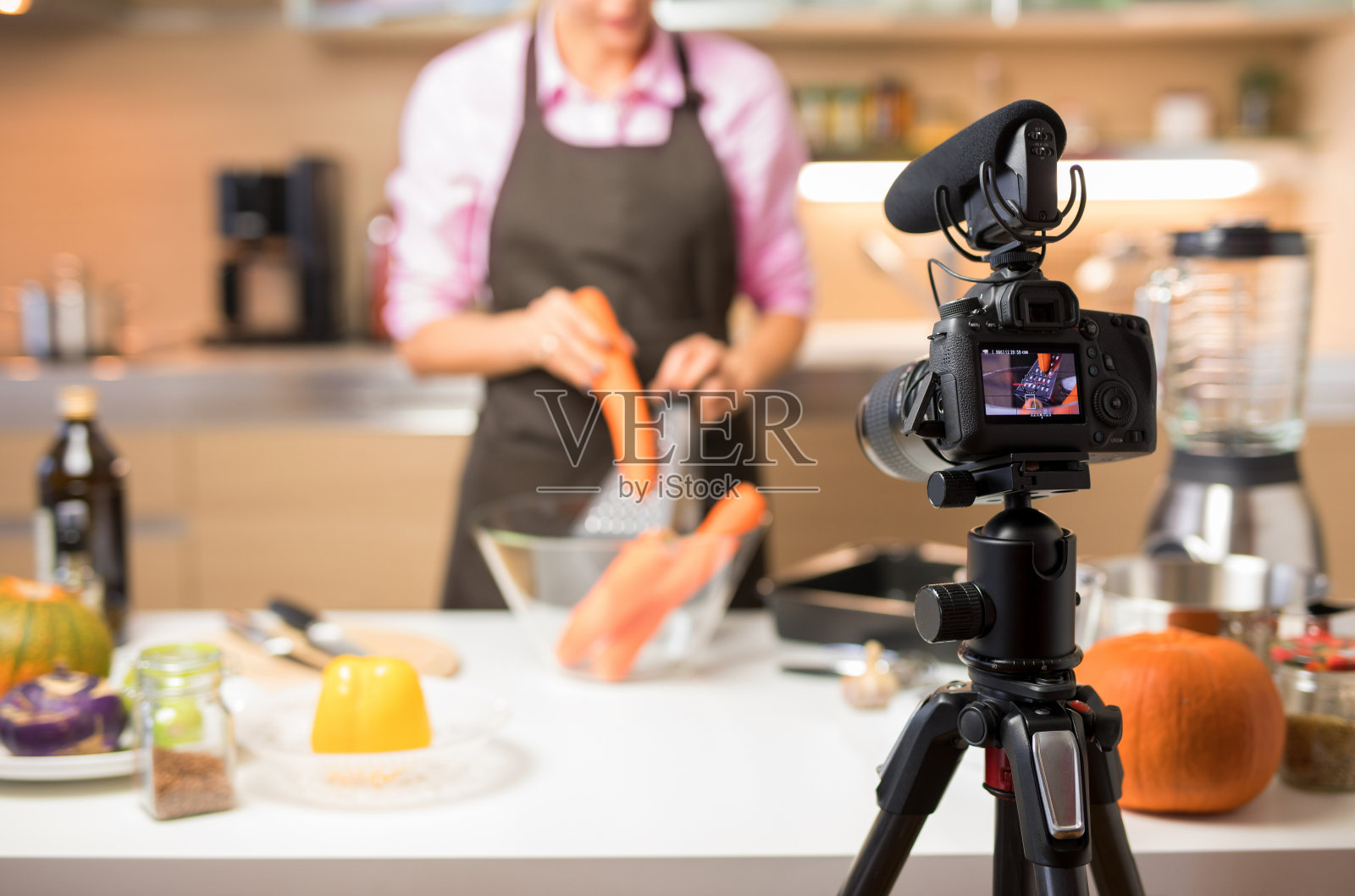 一名女子在网络视频博客上录制她的烹饪视频，专注于相机照片摄影图片
