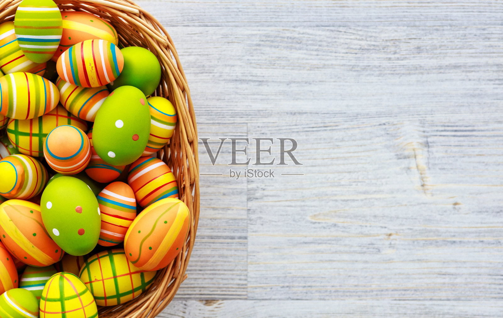 复活节的背景。彩色的鸡蛋篮子在木制背景照片摄影图片