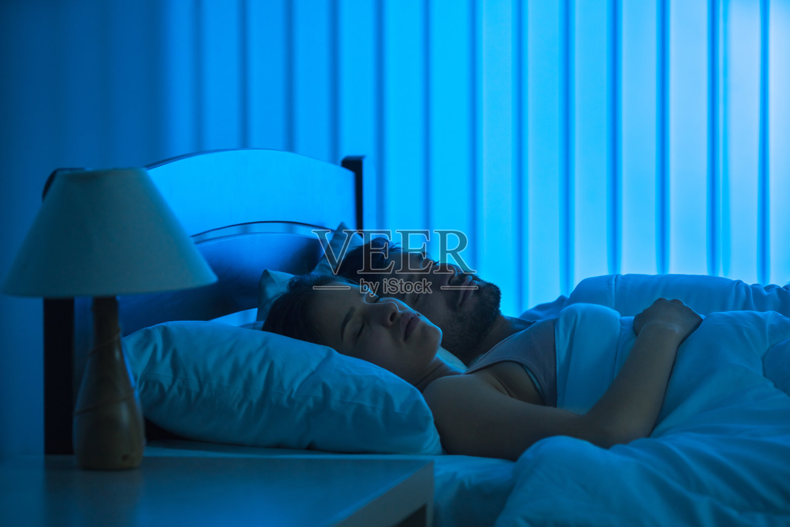 男人和女人睡在舒适的床上。夜间时间，全力抓好照片摄影图片