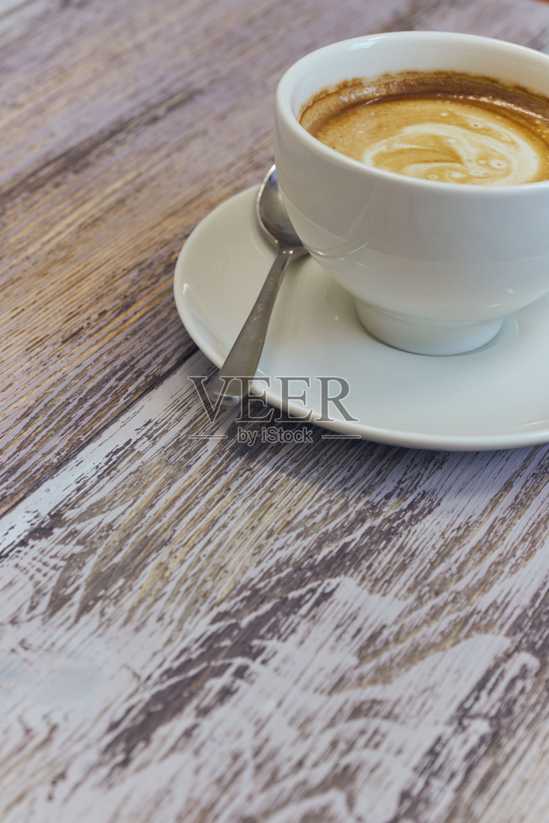 一张木桌上的咖啡杯。加牛奶的黑咖啡。木桌上放着香喷喷的饮料。垂直的观点。副本的空间。照片摄影图片
