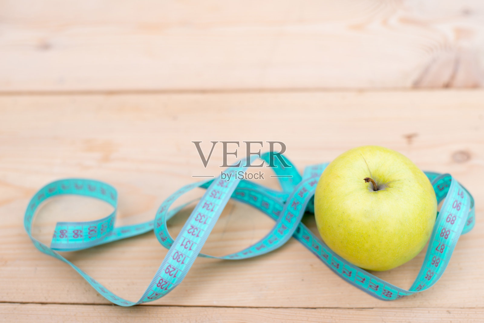 木背景上用卷尺测量的青苹果。饮食的概念。文本。副本的空间。照片摄影图片