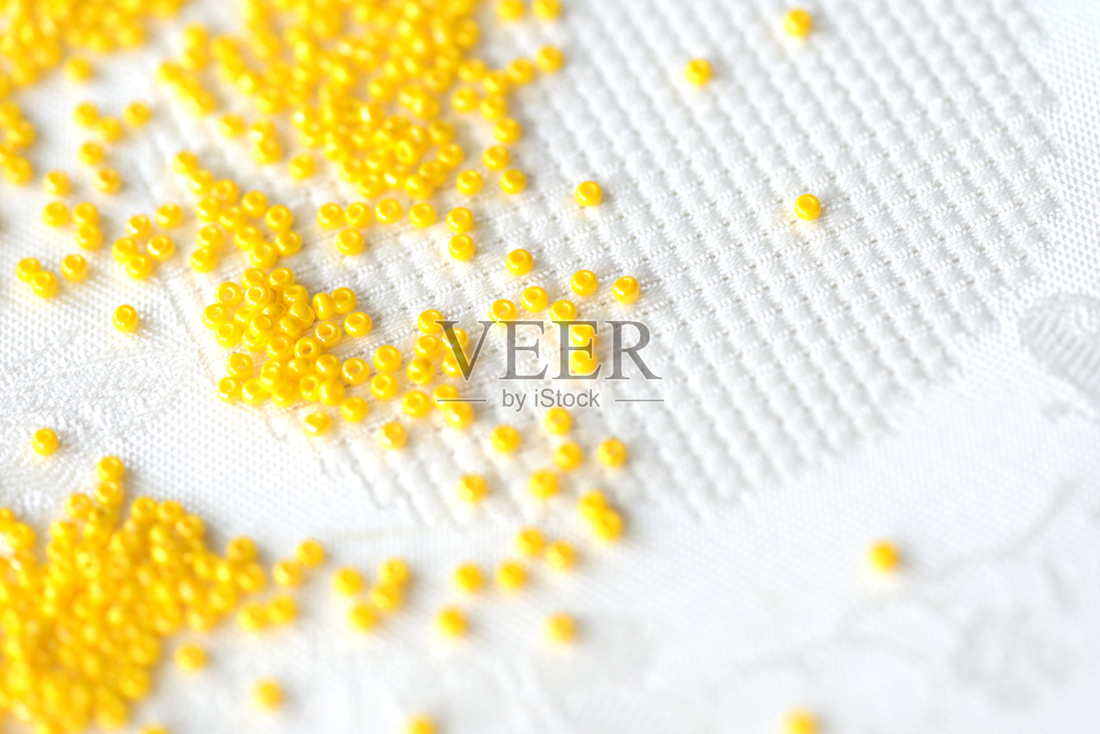 种子珠黄色散落在纺织品背景上，特写照片摄影图片
