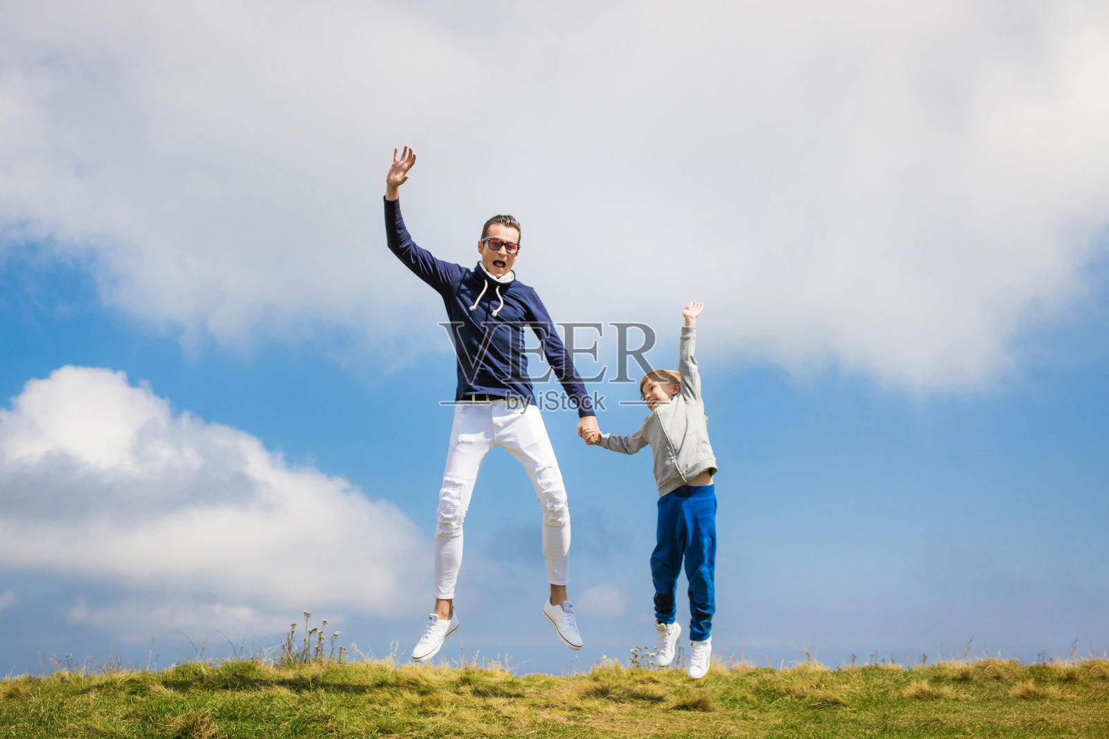 快乐的父亲和儿子在天空中跳跃。照片摄影图片