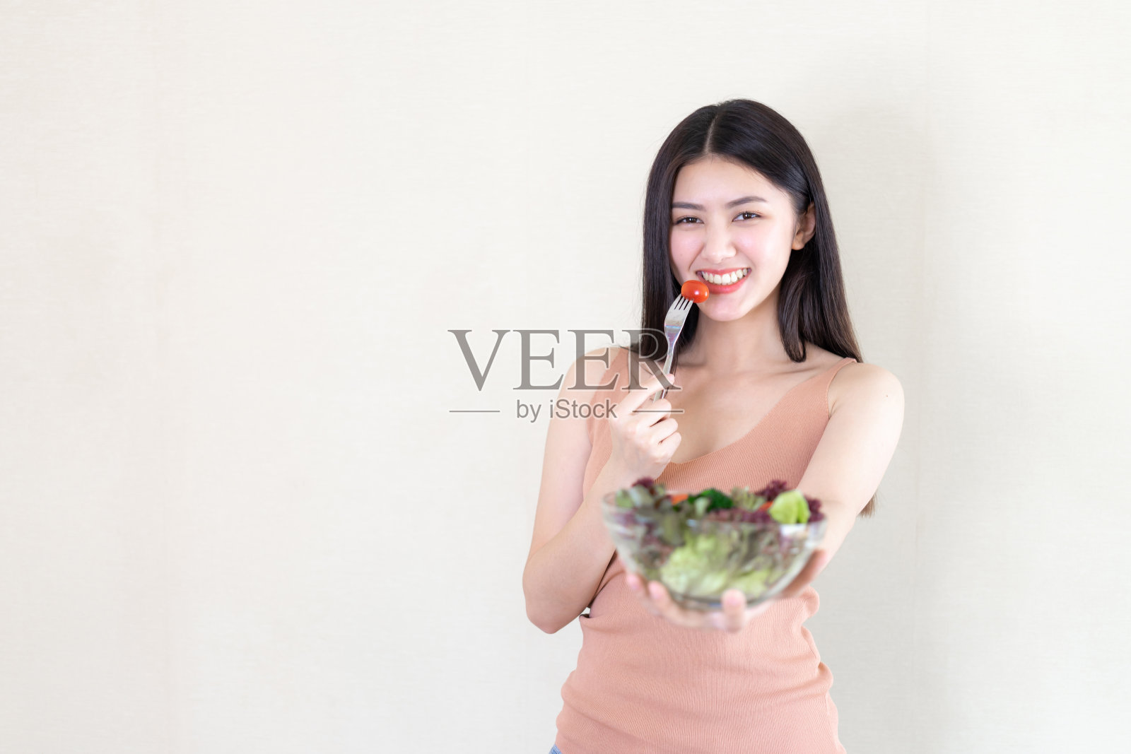 美丽的美丽女人亚洲可爱的女孩感到快乐的饮食食物新鲜的沙拉为健康的早晨，享受时间在她的家白色的卧室背景-生活方式美丽女人的概念照片摄影图片