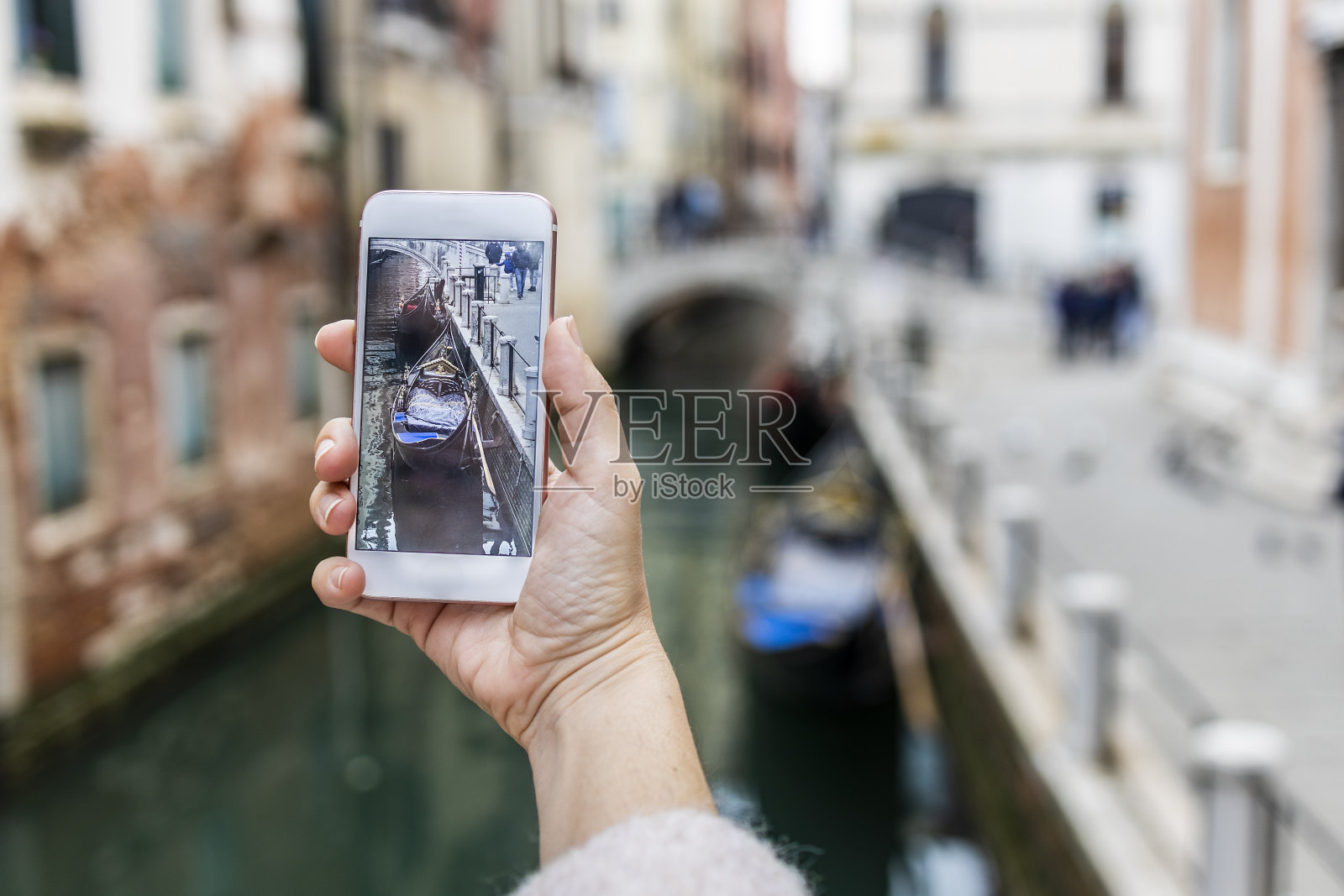 在威尼斯，一个女人的手在一艘平底船上拍照照片摄影图片