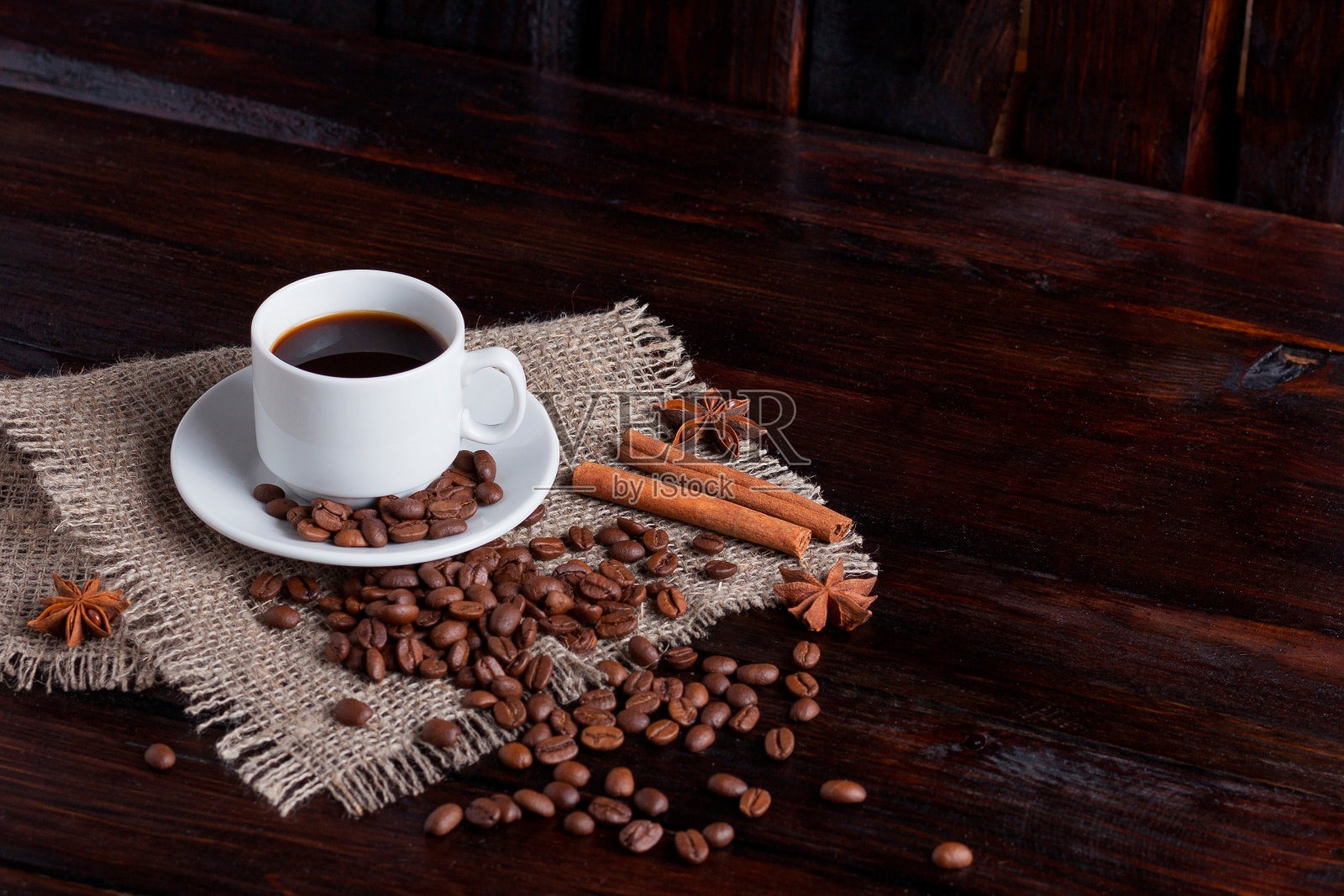 白色的咖啡杯与咖啡颗粒靠近亚麻织物在黑暗的复古背景照片摄影图片