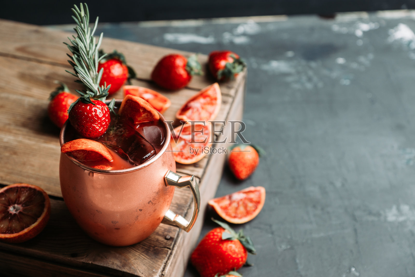 红橘子和草莓鸡尾酒铜杯(变种莫斯科骡子)在木制背景照片摄影图片
