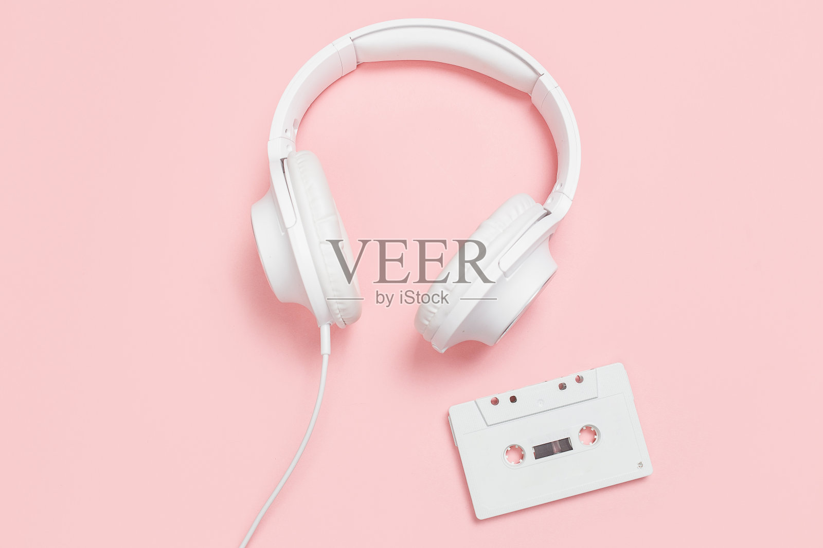粉红色背景上的白色盒式磁带和耳机照片摄影图片