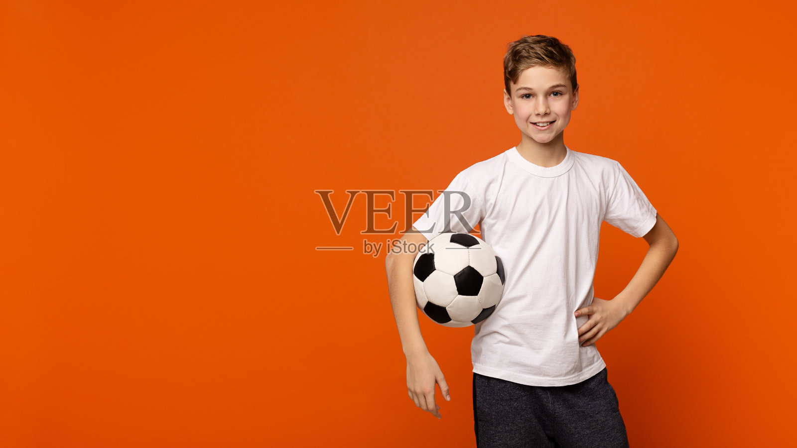 男孩与足球在橙色的工作室背景照片摄影图片