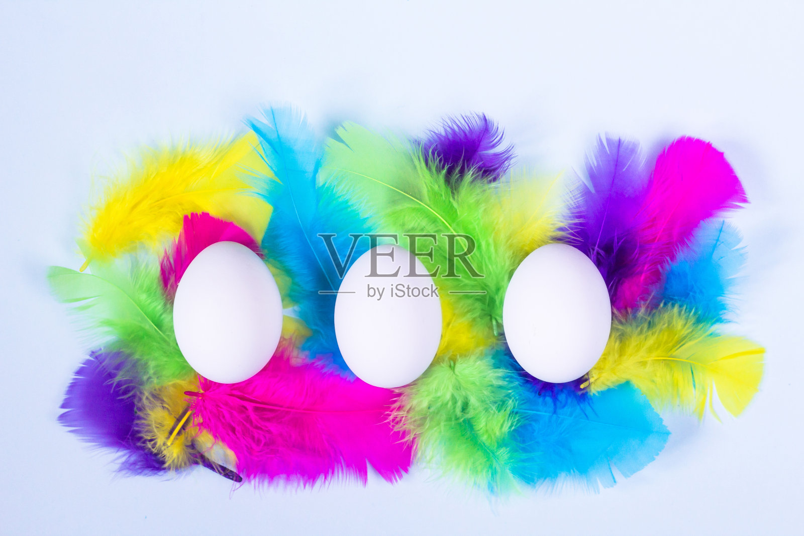 白色的蛋和彩色的羽毛在轻柔和的背景。复活节快乐的概念。简约风格，平铺。近距离照片摄影图片