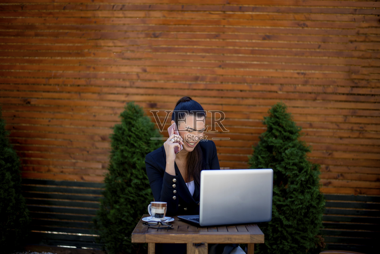 微笑的女商人用手机在咖啡店用笔记本电脑工作照片摄影图片