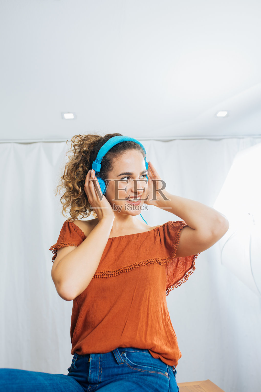 快乐的年轻女子戴着耳机在家边跳舞边听音乐。照片摄影图片