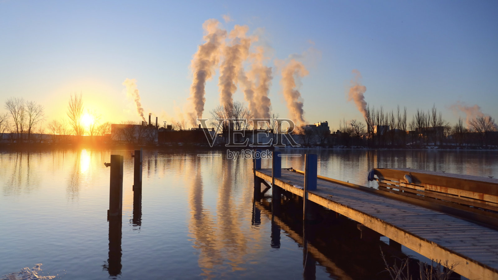 工厂的排放物在日出时反映在河流中。照片摄影图片