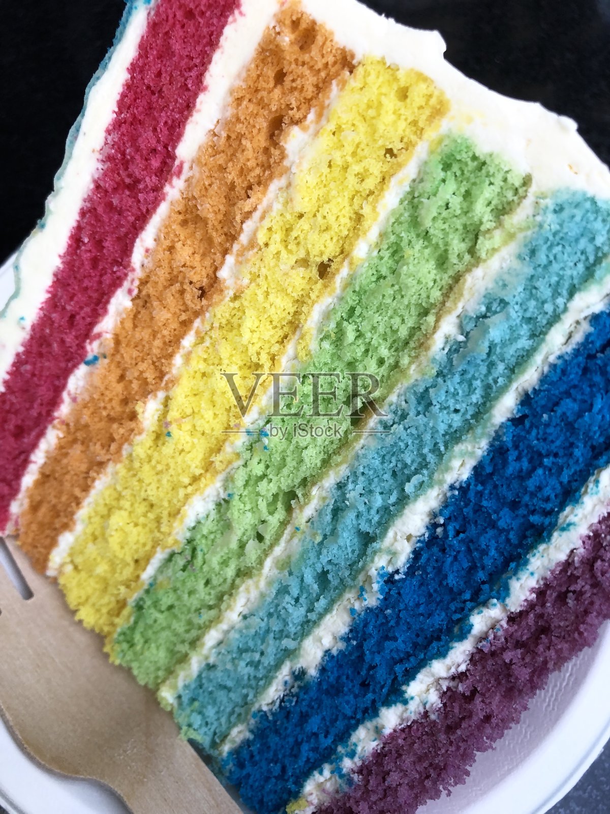 彩虹蛋糕的切片图像显示了多色海绵层与奶油糖霜的照片照片摄影图片