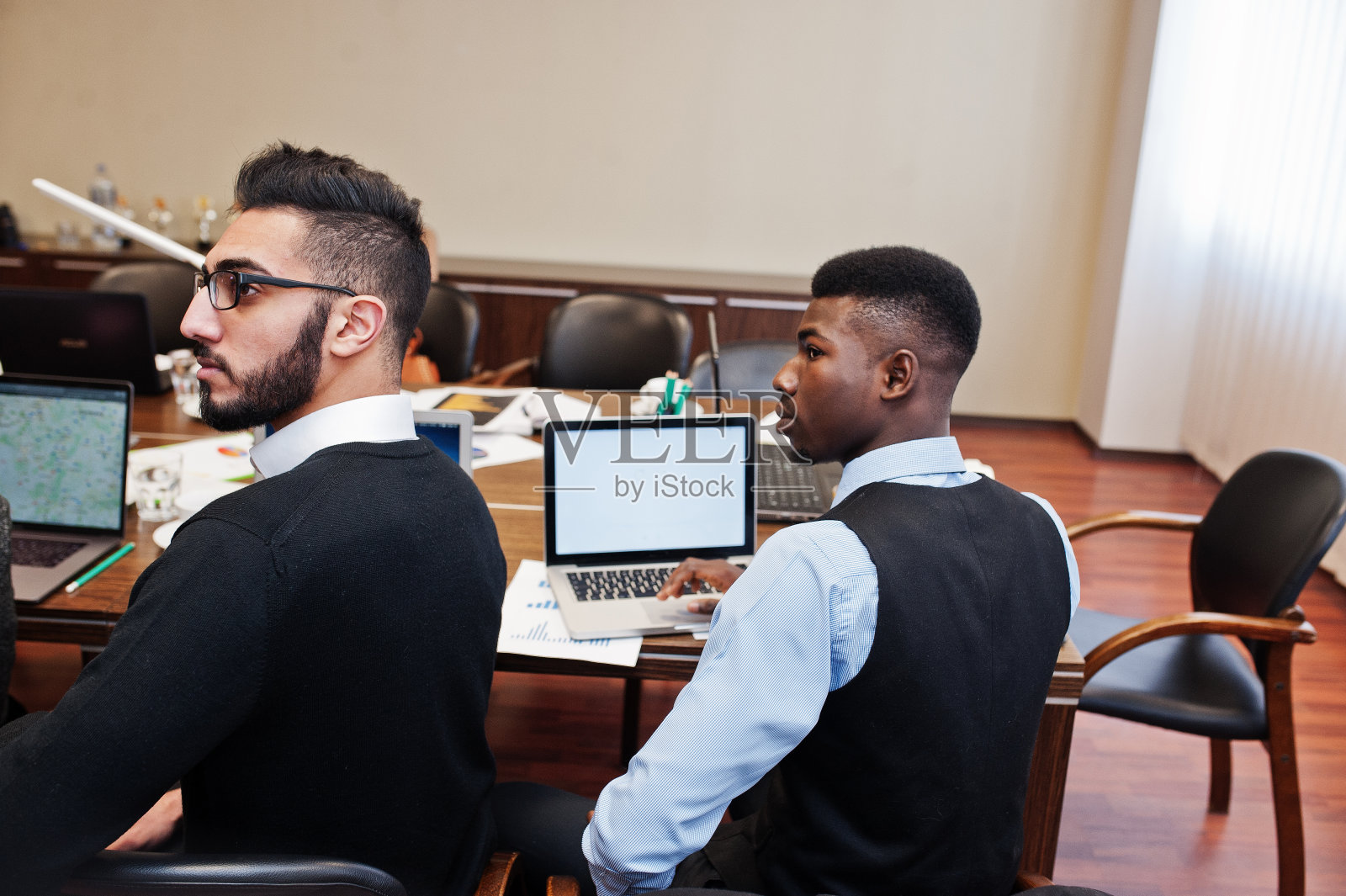 现代办公室里的多种族创意青年。一群年轻的商人正与笔记本电脑、平板电脑一起工作。成功的自由职业者在共同工作的团队。阿拉伯人和非洲人。照片摄影图片